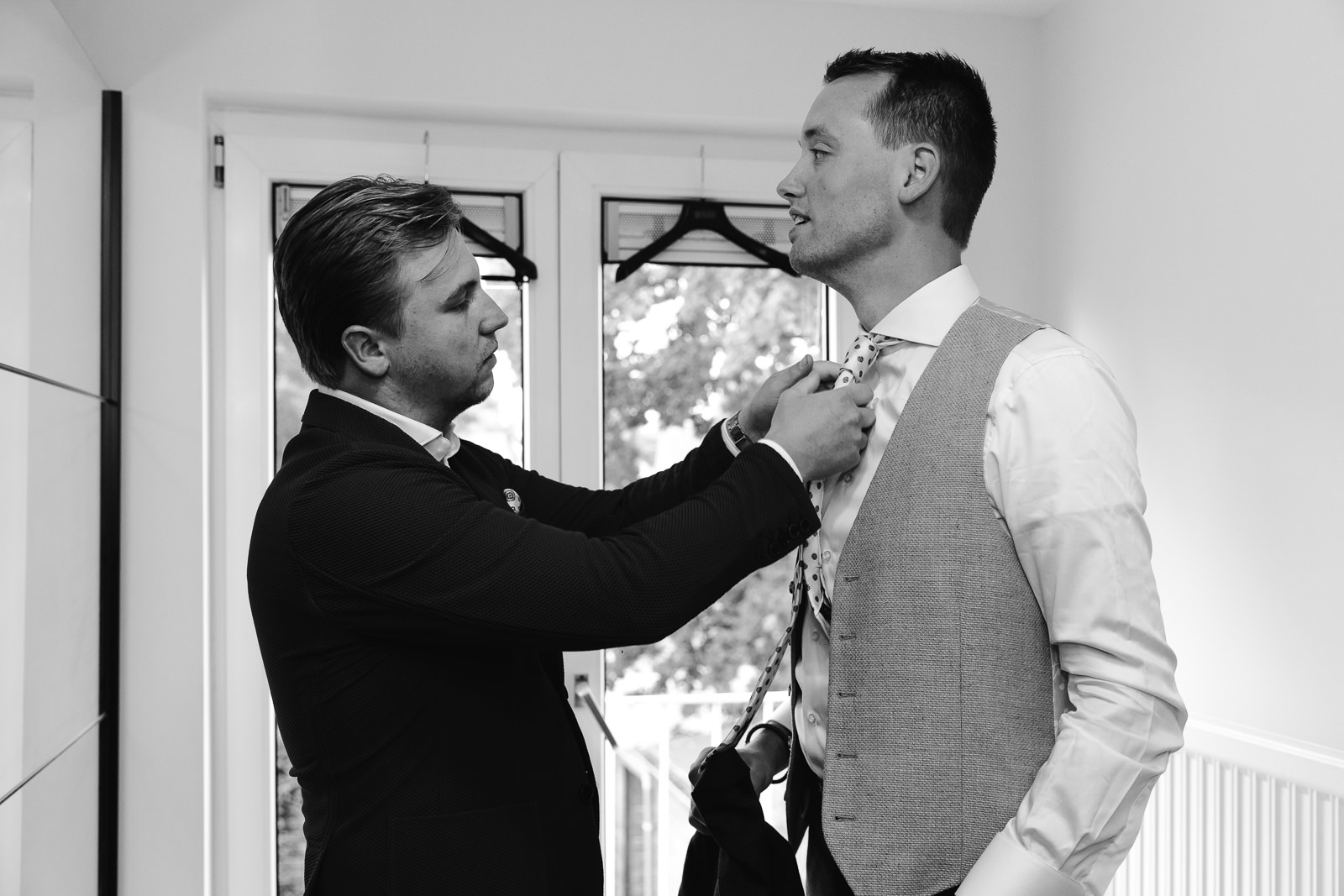 Broer helpt bruidegom met stropdas