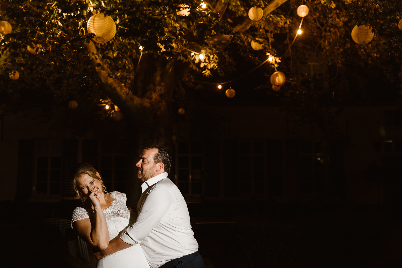 Portret bruidspaar met lampionnen in bomen