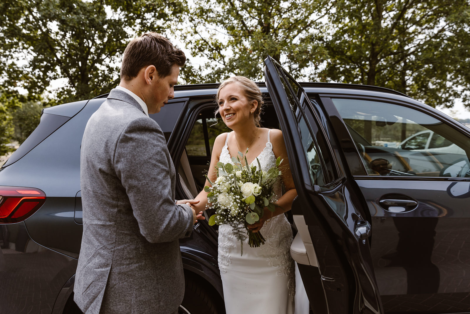 Bruidegom helpt bruid uit auto stappen