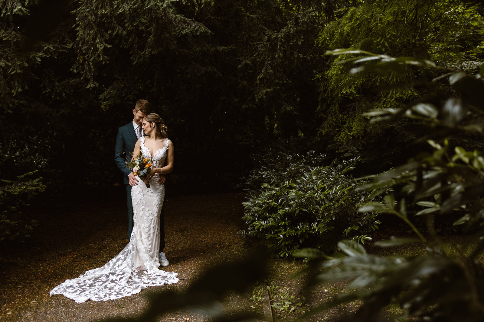 denise-van-duren-trouwfotograaf-betuwe-3 Bruidspaar poseert in prachtig natuurlijk licht tijdens een fotoshoot, omringd door een romantische en serene sfeer.